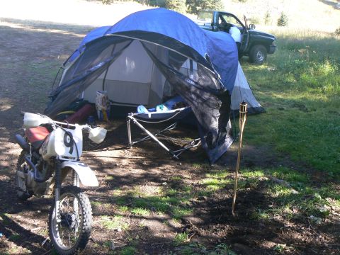 2006 Ford E350 - A dirt bike and campsite setup with a tent and pickup truck, suggesting an outdoor adventure or camping trip.