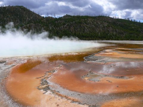 2006 Ford E350 - A geothermal hot spring emits steam, with vibrant mineral deposits creating patterns on the land's edge.