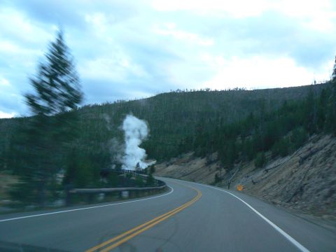 2006 Ford E350 - A road winds through a forested area with a plume of steam rising from a geothermal vent.