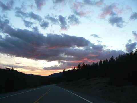 2006 Ford E350 - A highway stretches towards the horizon under a sky filled with dark, dramatic clouds tinged with pink.