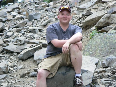2006 Ford E350 - Man sits on a rock in a rocky outdoor setting.