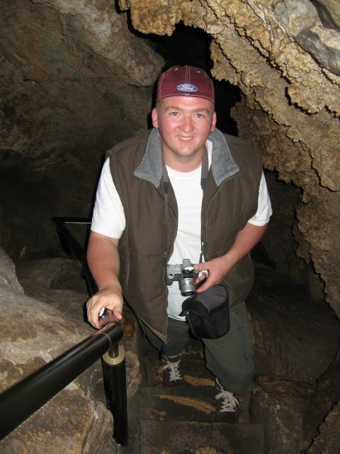 2006 Ford E350 - A man wearing a Ford-branded hat and a vest poses for a photo while descending stairs in a cave.