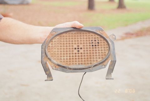 1976 Ford Ranchero - A rusty oval dash speaker, likely from an older vehicle, is held up for inspection.