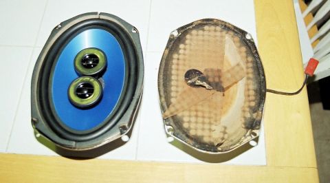 1976 Ford Ranchero - A pair of oval car speakers are shown, one in good condition and the other with a torn and burnt backing.