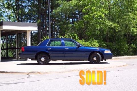 2001 Ford Crown Victoria - A blue 2001 Ford Crown Victoria is parked next to a building with trees in the background. The word "SOLD!" is overlaid on the image.