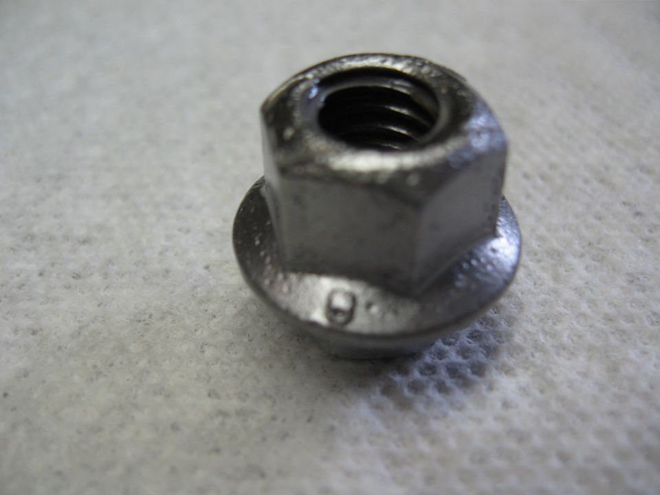 Close-up of a metal flanged nut with a '9' stamped on its base