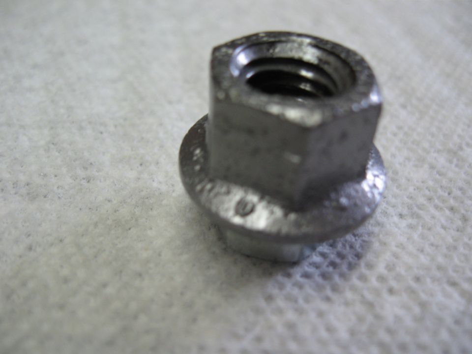 Close-up of a flanged hex nut on a white textured surface