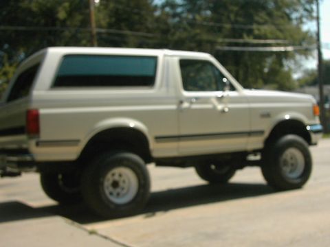 1987 Ford Bronco - Side view of a white 1987 Ford Bronco parked on pavement.