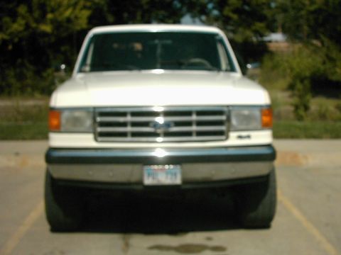 1987 Ford Bronco - Frontal view of a white 1987 Ford Bronco, showing its distinctive grille and headlights.