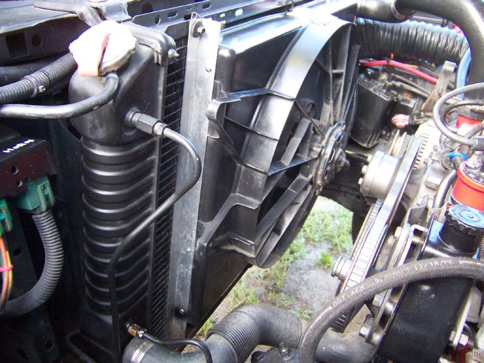 Fabricated a bracket out of 3/4 inch aluminum L stock.  Used 8 1/2 inch bolts and washers to mount the  L bracket to the fan shroud. The L bracket is bolted at the top using two bolts and capture nuts. The bottom of the bracket locks into the radiator support (no bolts).