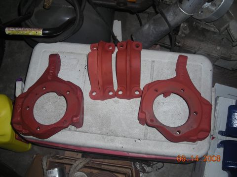 1993 Ford Bronco - Several red painted suspension components are laid out on a white cooler, ready for installation.