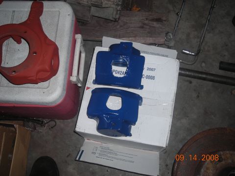 1993 Ford Bronco - Two newly painted blue brake calipers are displayed on a box, alongside other automotive parts.