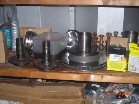 1993 Ford Bronco - Various automotive parts, including brake rotors and hubs, are organized on a wooden shelf.