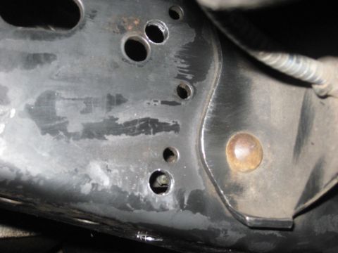 1991 Ford Bronco - Detail of a vehicle's frame, showing drilled holes and a bolt. The specific vehicle model is not identifiable.