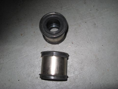 1991 Ford Bronco - Two metal and rubber bushings are shown on a gray concrete surface.
