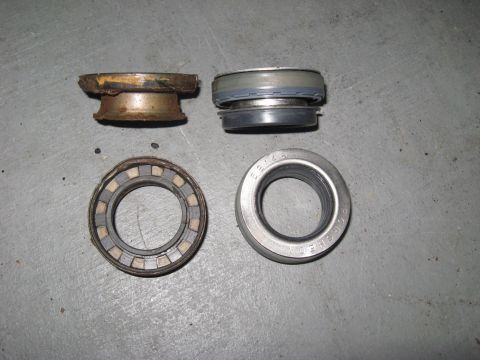 1991 Ford Bronco - Four automotive wheel bearings and seals are displayed on a concrete surface. One bearing shows significant wear.