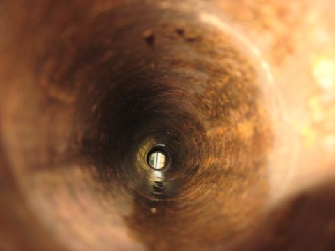 1991 Ford Bronco - View from inside a corroded pipe, showing a distant opening.