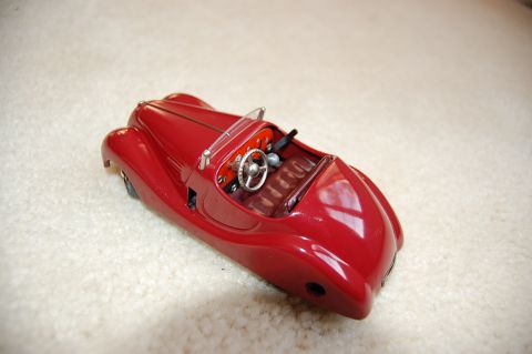1968 Chrysler Town & Country - A red toy car with a classic convertible design sits on a textured surface, showing its interior details.