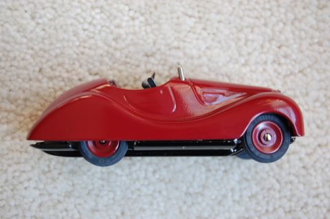 1968 Chrysler Town & Country - A small, red toy car with a vintage design is shown from the side on a textured carpet.
