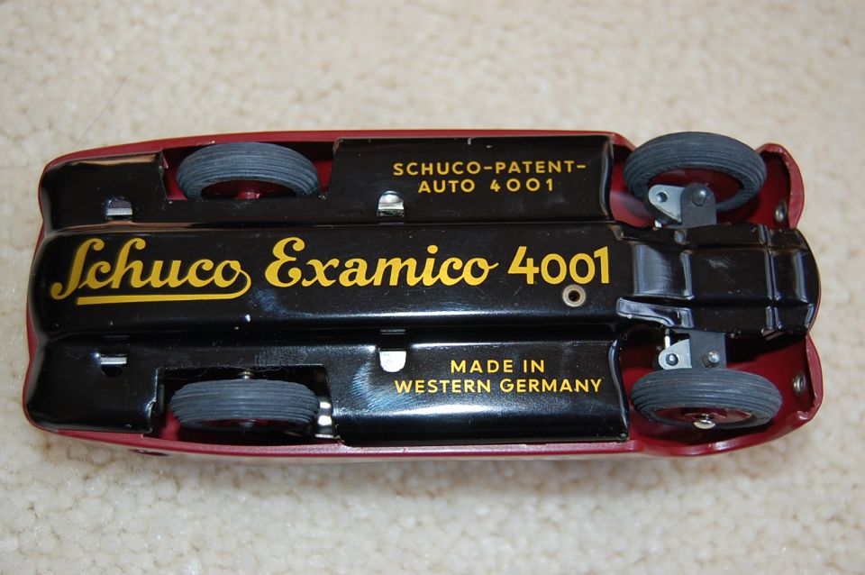 Underside of red Schuco Examico 4001 tin toy car with gold text on black baseplate