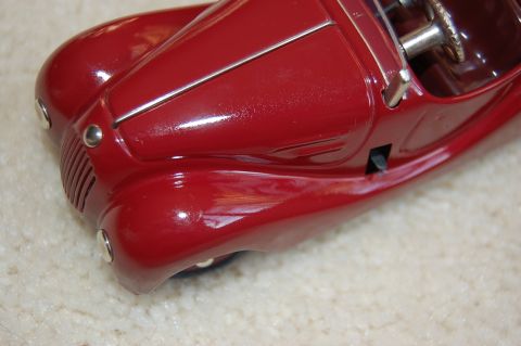 1968 Chrysler Town & Country - A close-up view of the front of a red toy car, resting on a carpeted surface.