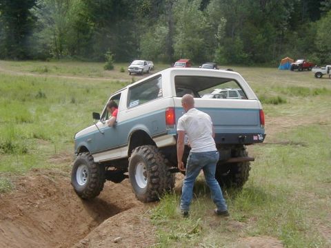1988 Ford Bronco - A modified Ford Bronco navigates an off-road course with other vehicles in the background.