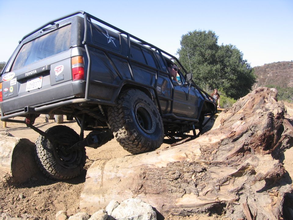 Modified Toyota 4Runner with roll cage and large tires navigating a rocky trail