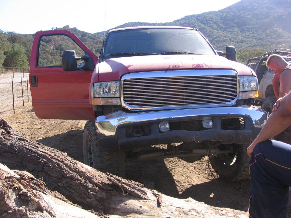 Red Ford F-250 truck with driver's door open, chrome grille, and lifted suspension