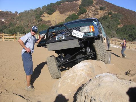 1989 Ford Bronco - A modified 1989 Ford Bronco navigates rocky terrain with a man standing nearby.