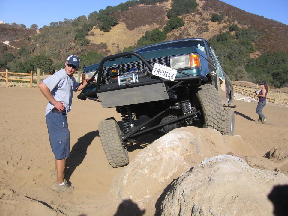 Green 1989 Ford Bronco with winch and custom bumper on rocks
