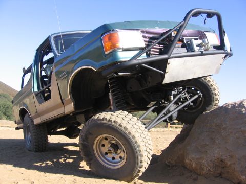 1989 Ford Bronco - Modified 1989 Ford Bronco tackling an off-road obstacle with its suspension articulated.