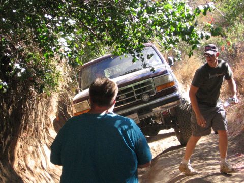 1989 Ford Bronco - A maroon SUV navigates a narrow dirt path with two people nearby.