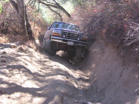 1989 Ford Bronco - Bronco tackling a challenging off-road path on a sunny day.