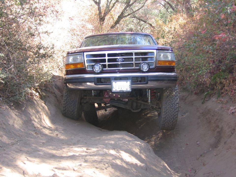 Red Ford truck with aftermarket lights on a dirt trail