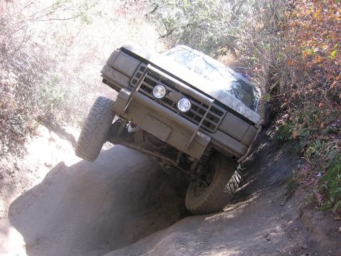 1989 Ford Bronco - Vehicle navigating a challenging off-road trail with steep inclines and loose dirt.