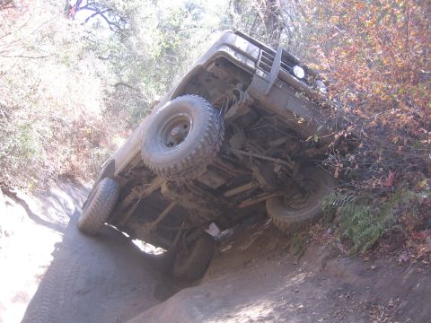 1989 Ford Bronco - This vehicle appears to be stuck on a challenging off-road trail, tilted precariously on its side.