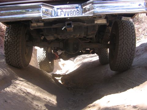 1989 Ford Bronco - Off-roading on a dirt trail, showing the rear axle and tires. California plate LFVV808.