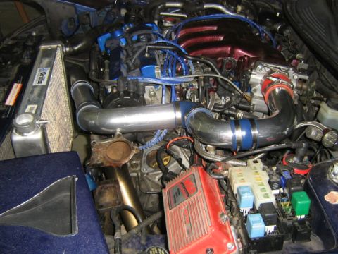 1995 Ford Probe - Close-up view of a modified engine bay, showing turbocharger plumbing and various engine components.