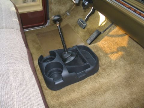 1979 Ford Bronco - Vehicle interior showing floor-mounted shifter, cup holder console, and pedals.