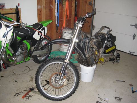 1993 Suzuki RMX250 - Dirt bike disassembled in a garage, with a second dirt bike visible.