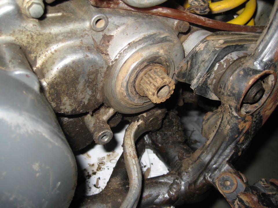 Grimy splined countershaft protruding from a motorcycle engine case