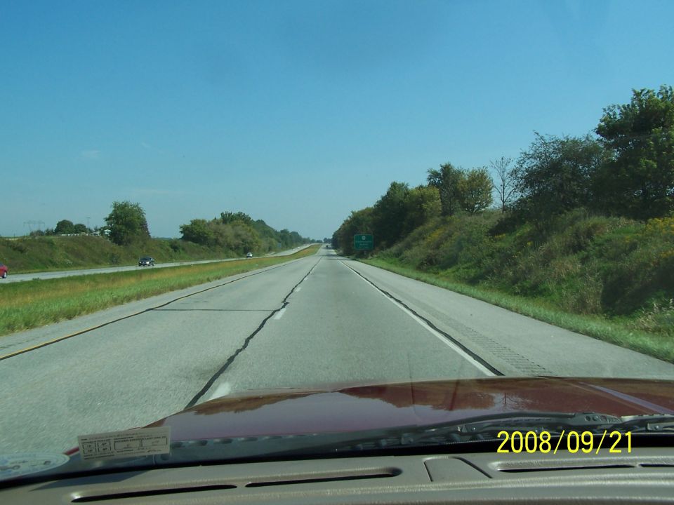 View over dark red hood driving down a divided highway lined with trees, dated 2008/09/21