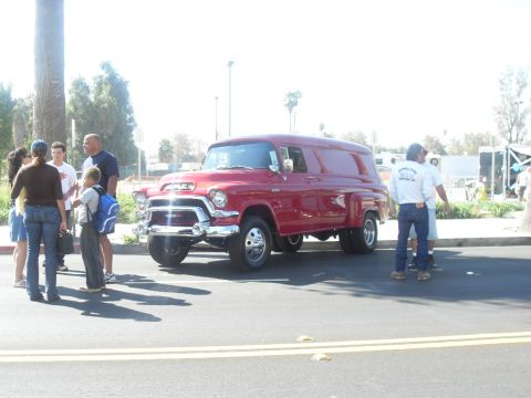 1990 Ford Bronco - A classic red GMC panel van, likely from the mid-1950s, is parked outdoors with several people gathered around.