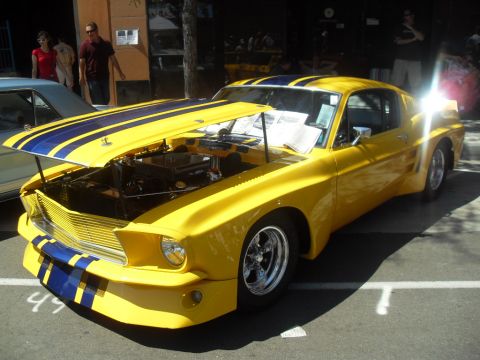 1990 Ford Bronco - Customized 1967 Ford Mustang with racing stripes and open hood at a car show.