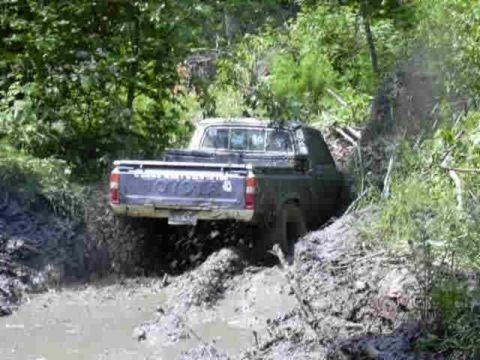 1988 Ford Bronco - This Toyota pickup is navigating a difficult muddy trail, kicking up water and dirt.
