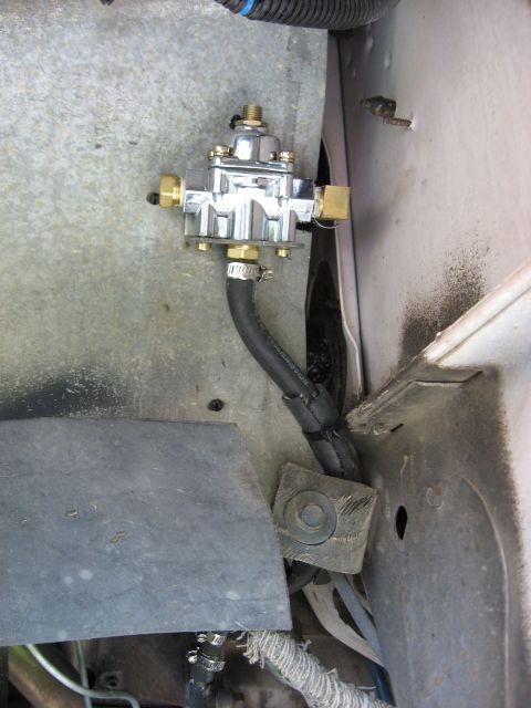 1979 Ford Bronco - A chrome fuel pressure regulator is mounted with a black hose and metal bracket.