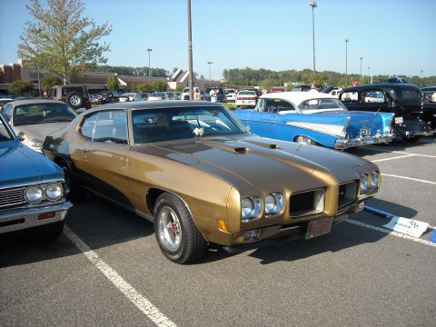 1979 Ford F-150 - A gold 1970 Pontiac GTO is parked at a car show next to other classic vehicles.