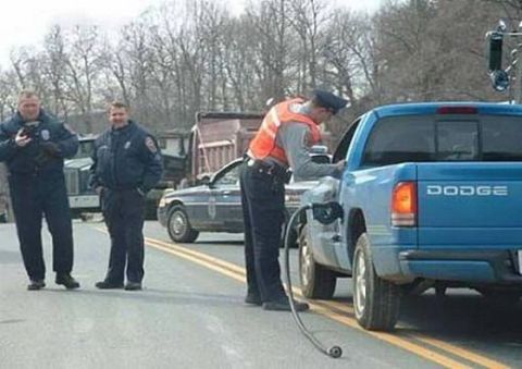 1990 Ford Bronco - Two police officers in uniform stand on a road next to a blue Dodge pickup truck while another officer in an orange vest appears to be inte…