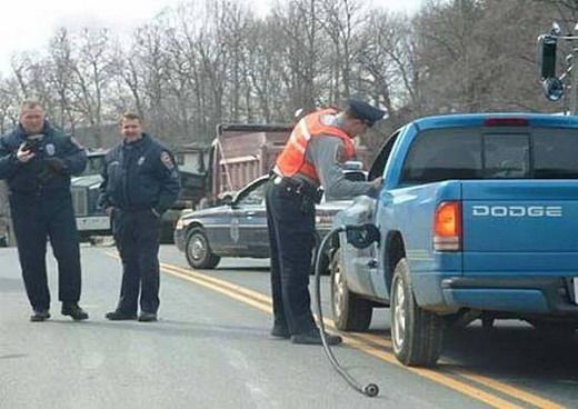 Police officers at a roadside stop with a blue Dodge pickup truck.