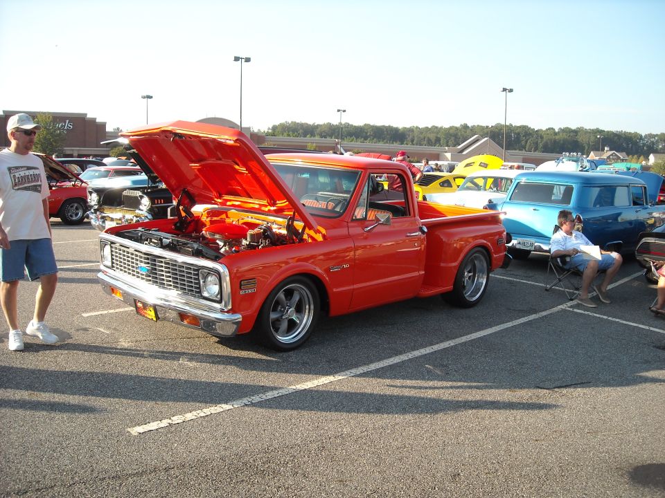 Red Chevrolet C10 stepside pickup with hood open at a car show